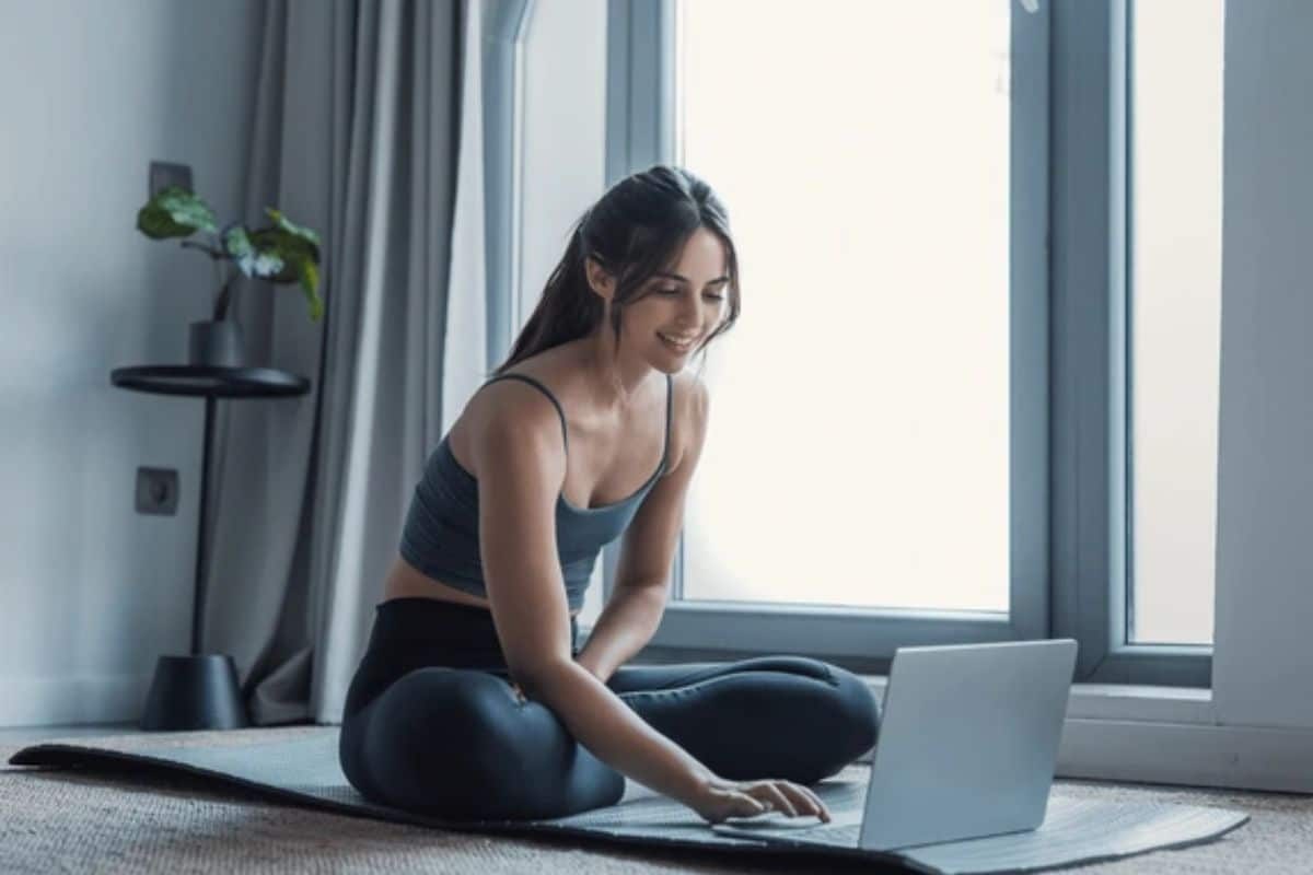 Femme avec ordinateur sur son tapis de sport