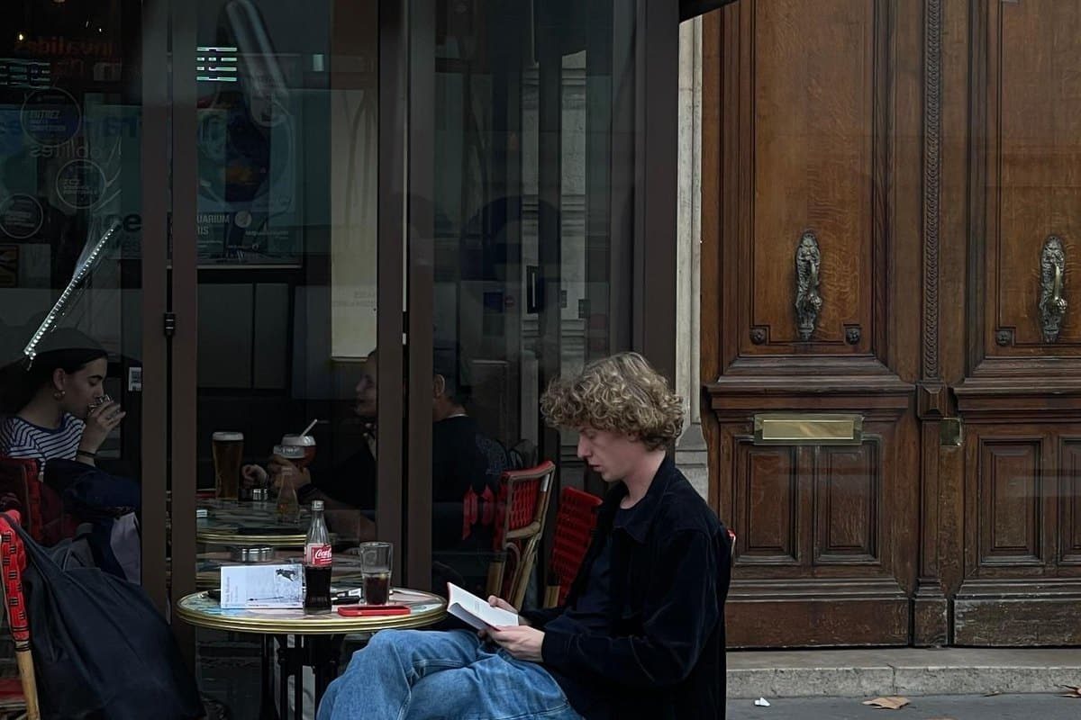 Jeune homme lisant en terrasse